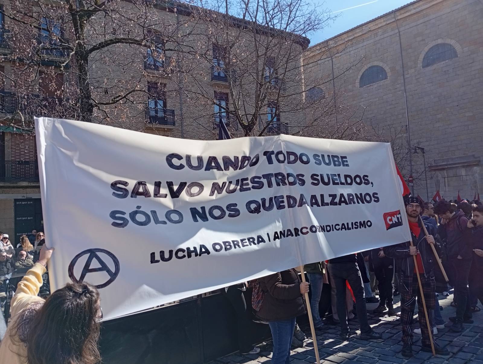 Manifestación con una gran pancarta de CNT que denuncia la subida de precios frente al estancamiento salarial, durante una movilización sindical en la calle.